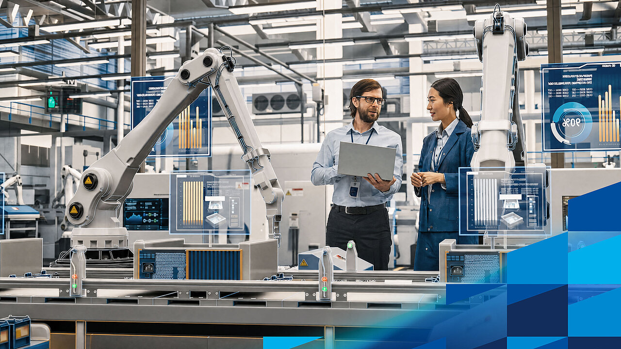 Two skilled workers are analysing production data on a tablet in an automated manufacturing environment.