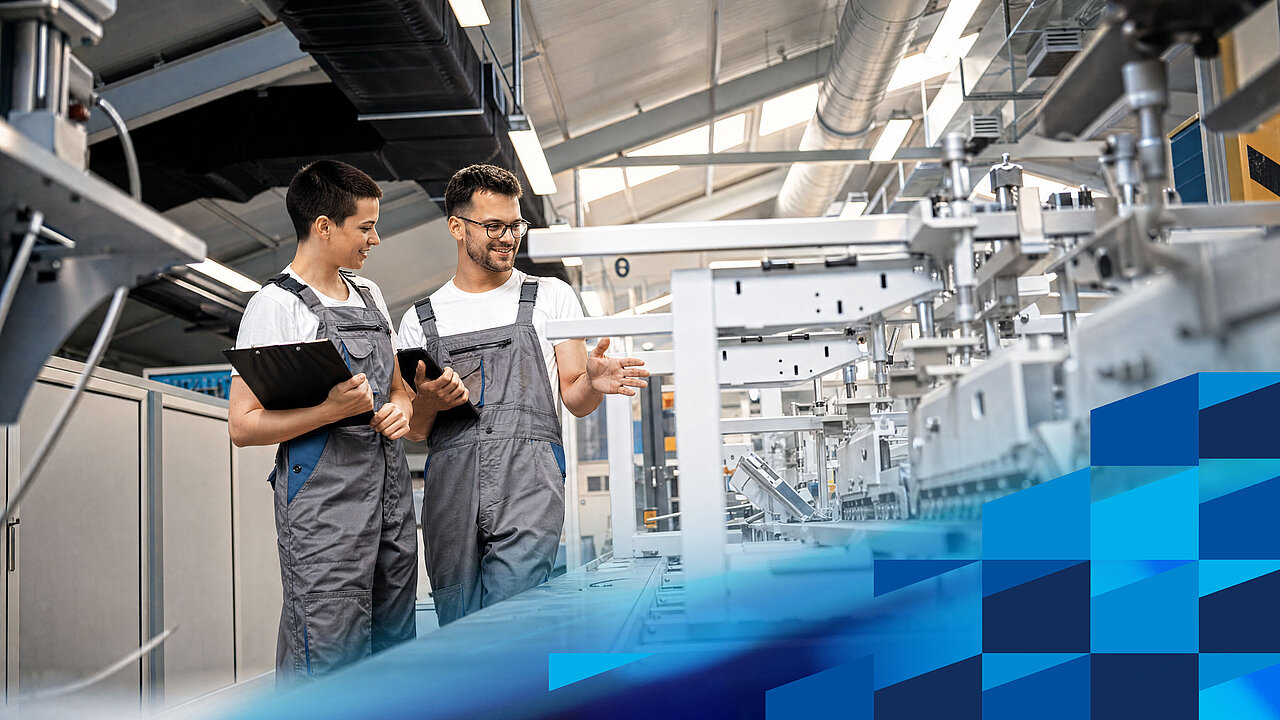 Two skilled workers are analysing processes and production data on an automated production line.